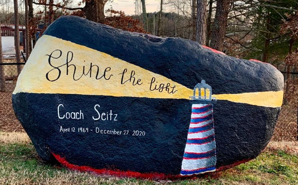 A painted rock on Lincoln Charter’s campus in Denver, N.C., honors Jamie Seitz, who taught elementary school PE and coached high school basketball and golf for the school before dying of COVID-19. The red-and-blue colors of the lighthouse represent Seitz’s favorite NFL team, the Buffalo Bills.