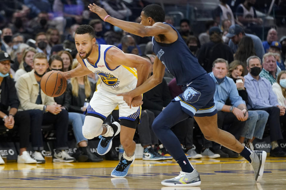 Golden State Warriors guard Stephen Curry, left, drives against Memphis Grizzlies guard De'Anthony Melton during the first half of an NBA basketball game in San Francisco, Thursday, Oct. 28, 2021. (AP Photo/Jeff Chiu)