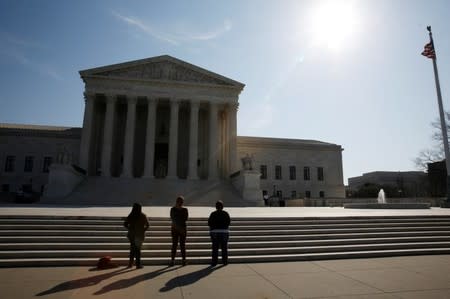 Three anti-abortion protestors are seen outside U.S. Supreme Court building is seen in Washington, March 16, 2016. REUTERS/Jim Bourg