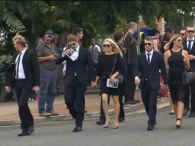 Hughes' teammates leave after the funeral.