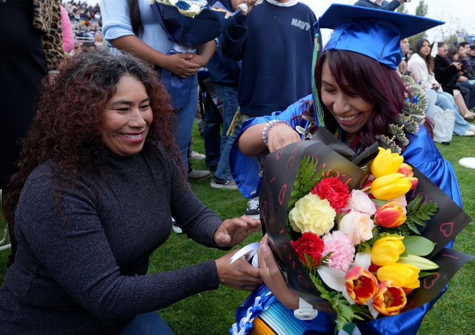 Olga Mendoza gives her daughter Jennifer Cortez flowers near the end of the Oxnard College graduation at Condor Stadium on Thursday.