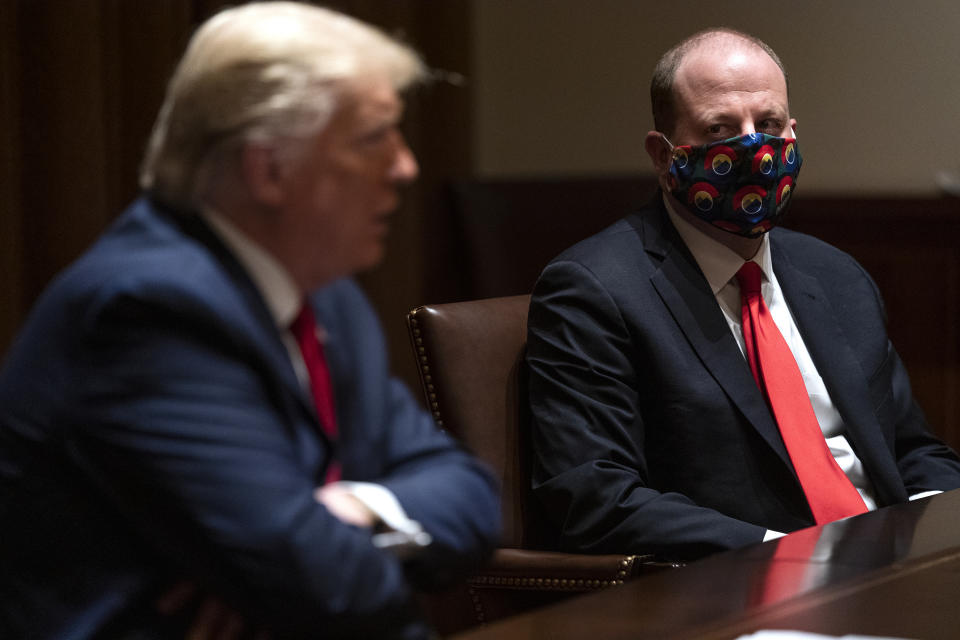 Colorado Gov. Jared Polis listens as President Donald Trump speaks during a meeting on the coronavirus response, in the Cabinet Room of the White House, Wednesday, May 13, 2020, in Washington. (AP Photo/Evan Vucci)