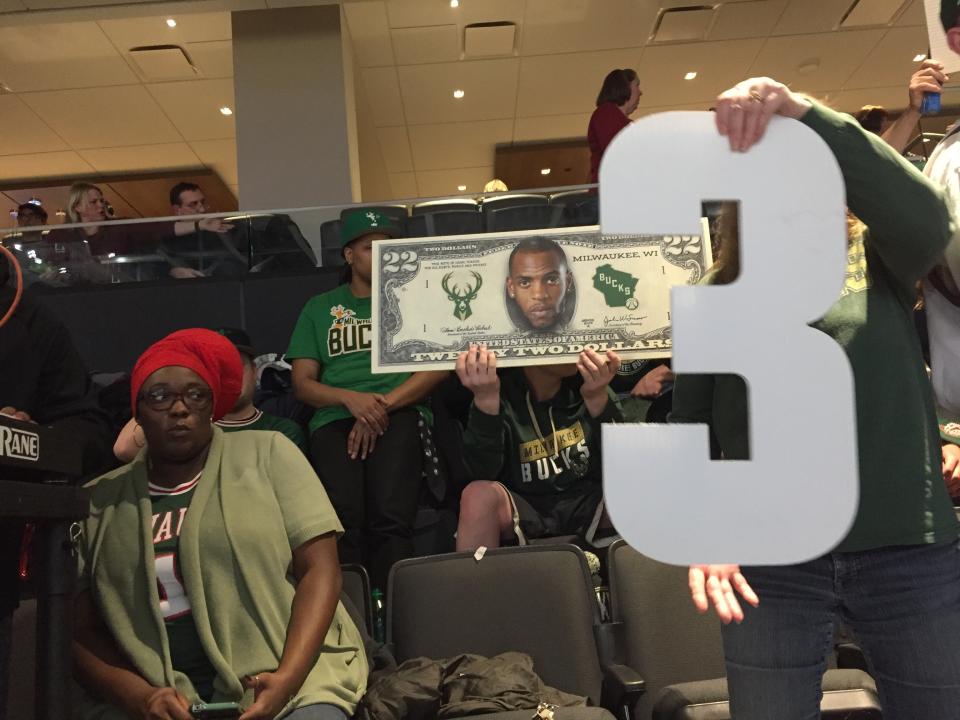 The Clutch Crew comes prepared with signs, big heads and even a $22 bill with Khris Middleton's face on it. (Yahoo Sports)