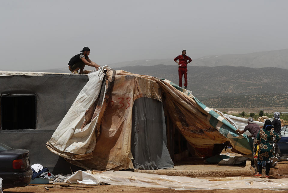 Syrian men remove cloth from their makeshift shelter, as they prepare to evacuate an informal refugee camp after a fight broke out last week between camp residents and Lebanese firefighters who arrived to put out a fire, in Deir Al-Ahmar, east Lebanon, Sunday, June 9, 2019. Dozens of Syrian refugees have dismantled their tents in a camp they lived in for years in eastern Lebanon after authorities ordered their evacuation following a brawl with locals. Lebanon hosts over 1 million Syrian refugees who fled the war next door since 2011, overwhelming the country of nearly 5 million. (AP Photo/Hussein Malla)