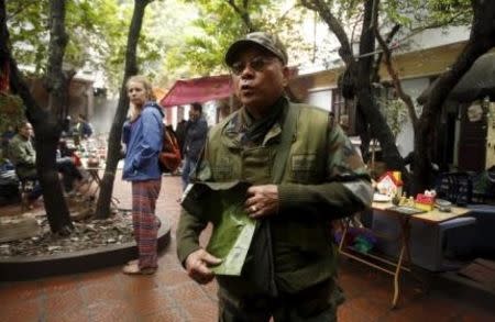 Vietnamese veteran Vu Van Bao, wearing the uniform of the U.S. Army's Alpha team, shows off a bag containing a claymore mine which was used during the Vietnam War, at an old items market in Hanoi March 14, 2015. REUTERS/Kham