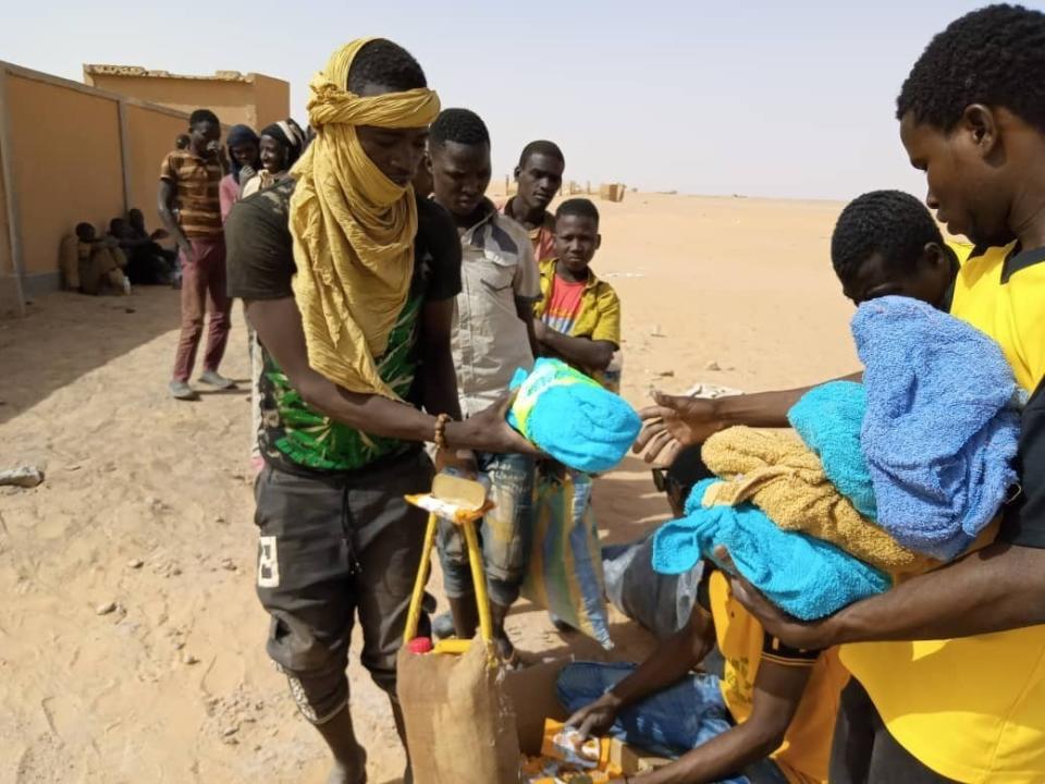 In this April 25, 2020 photo provided by IOM Niger, some of nearly 100 Nigeriens arrive in Assamaka, Niger, on foot from Algeria and now must be quarantined for two weeks at the remote Sahara border settlement, where water is scarce and midday temperatures reach over 110 degrees (45 degrees Celsius). Globally, coronavirus has marooned thousands of migrants in some of the world's harshest conditions on land and at sea. (IOM Niger via AP)