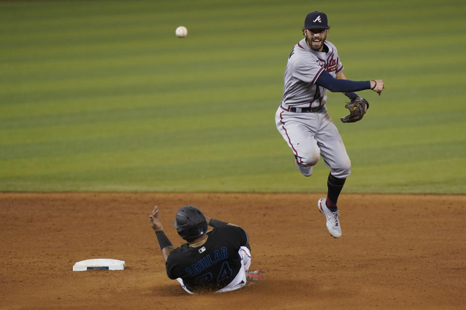 Atlanta Braves shortstop Dansby Swanson, right, throws to first to attempt a double play as Miami Marlins' Jesus Aguilar, left, is out at second during the eighth inning of a baseball game, Saturday, June 12, 2021, in Miami. Marlins' Adam Duvall was safe at first. (AP Photo/Wilfredo Lee)