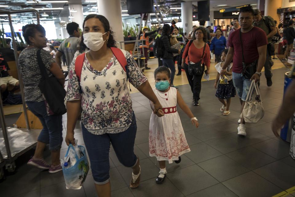 Wearing masks, passenger Gladys Ruiz Torres walks with her daughter Natali Oliva to the departure lounge at the international airport in Lima, Peru, Friday, March 6, 2020. Peruvian President Martin Vizcarra announced the first case of the new coronavirus in the country. (AP Photo/Rodrigo Abd)