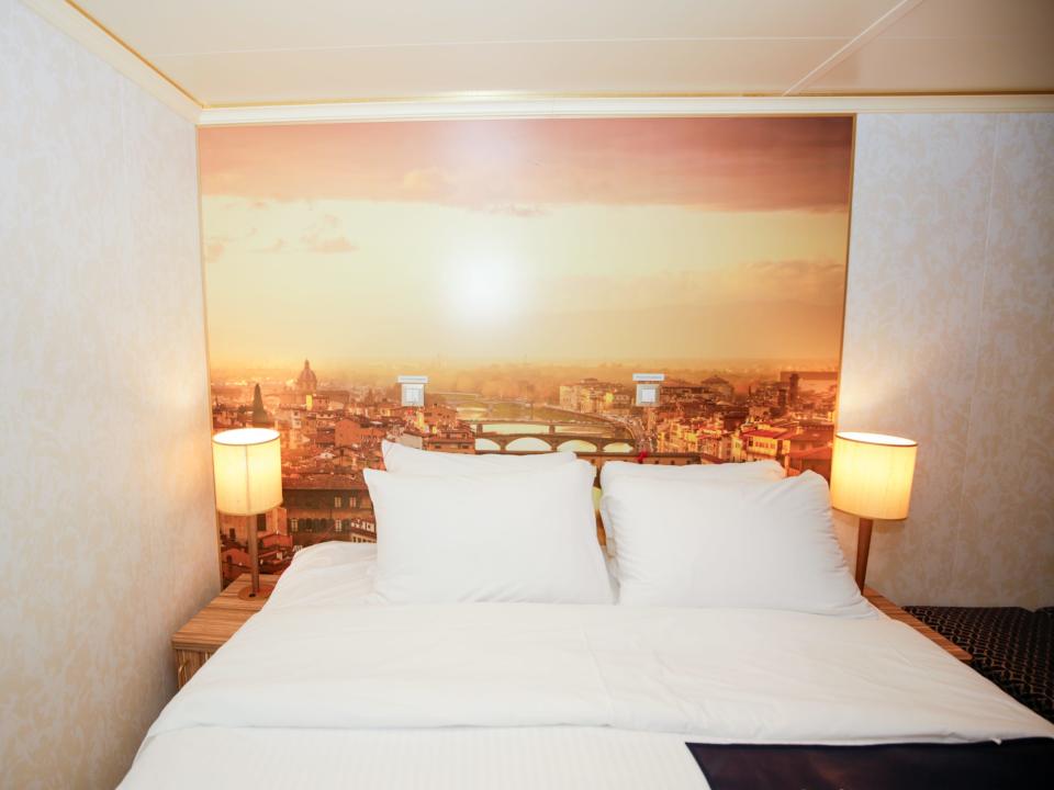 a bed in front of a photo of Florence, Italy in my Carnival Firenze cruise cabin