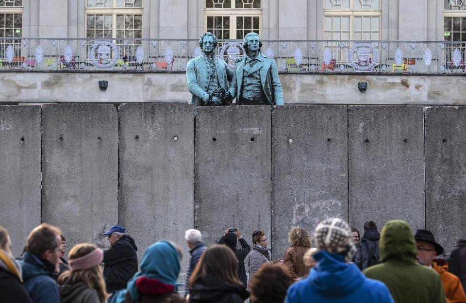 A wall, an art performance of the National Theatre Weimar, stand in front of the memorial of German poets Johann Wolfgang von Goethe, left, and Friedrich Schiller, right, prior the 30th anniversary of falling Berlin wall in Weimar, Germany, Wednesday, Oct. 30, 2019. With the temporary installation of 17 wall elements, the National Theatre recall the events of autumn 1989. The artist Christina Wildgrube designs this 'wall'. Unlike the former Belin wall, the art project should not create a long-term separation, but bring people together. (AP Photo/Jens Meyer)