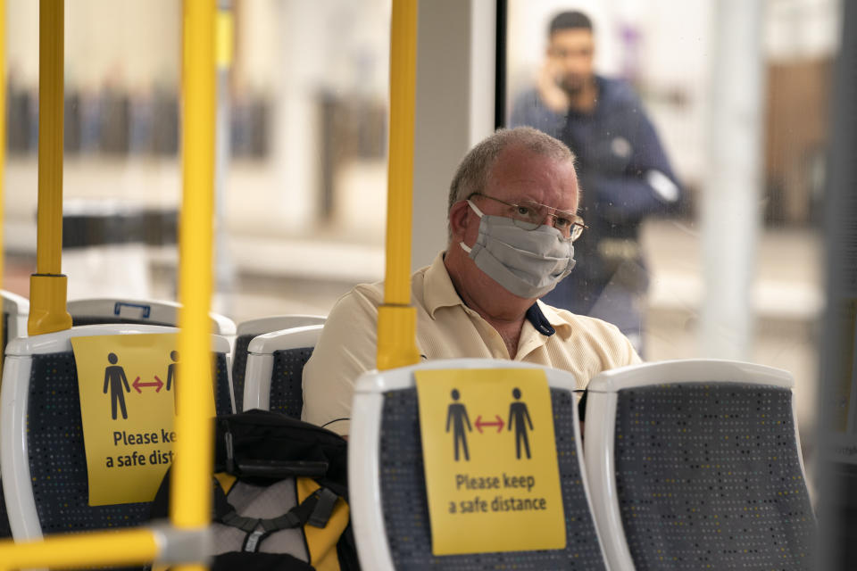 LONDON, June 15, 2020 -- A man wearing a face mask sits in a tram at Manchester Victoria Railway Station in Manchester, Britain, on June 15, 2020. As non-essential stores reopen and more students head back to schools in England on Monday for the first time in almost three-months, a new rule also came into force requiring people travelling on public transport to wear face coverings during their journeys. Under the new rule, people in England travelling on trains, buses and commuter ferries, as well as the London Underground, must wear face coverings during their journeys. (Photo by Jon Super/Xinhua via Getty) (Xinhua/ via Getty Images)