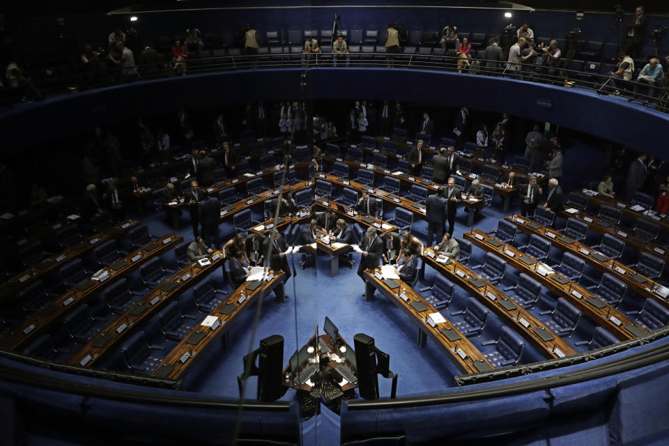 The Senate, seen reflected in a mirror, left, holds a final vote on pension reform in Brasilia, Brazil, Tuesday, Oct. 22, 2019. The most meaningful impact of the reform is the establishment of a minimum age for retirement at 65 for men and 62 for women. (AP Photo/Eraldo Peres)