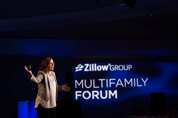 Person speaking on stage with a backdrop showing Zillow Group Multifamily Forum.