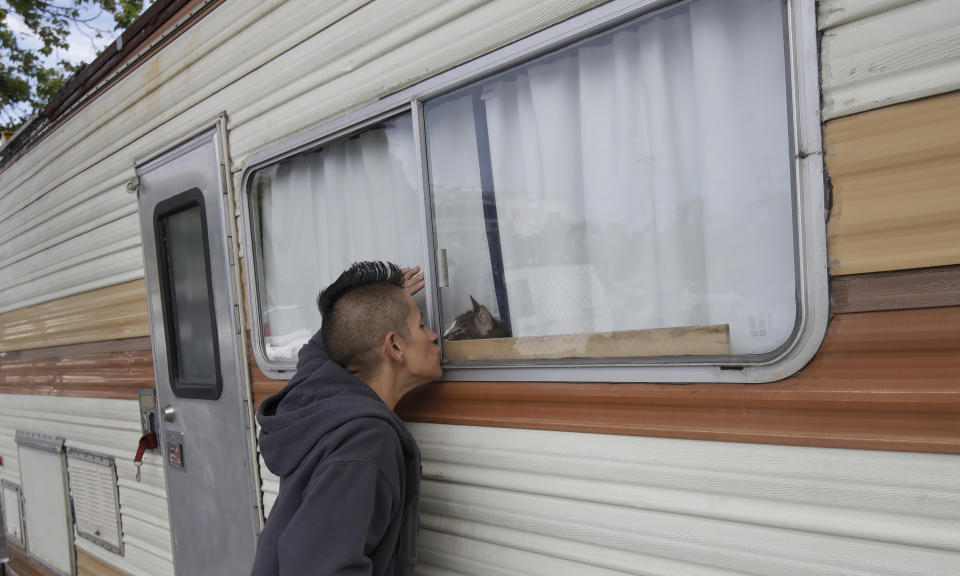 This Thursday, June 27, 2019, photo shows Shanna Couper Orona kissing her cat Maison through a window of her RV parked along a street in San Francisco. A federally mandated count of homeless in San Francisco increased 17% in two years, driven in part by a surge of people living in RVs and other vehicles. (AP Photo/Jeff Chiu)