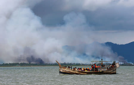 Smoke is seen on Myanmar's side of border as a boat carrying Rohingya refugees arrives on shore after crossing the Bangladesh-Myanmar border through the Bay of Bengal, in Shah Porir Dwip, Bangladesh September 11, 2017. REUTERS/Danish Siddiqui