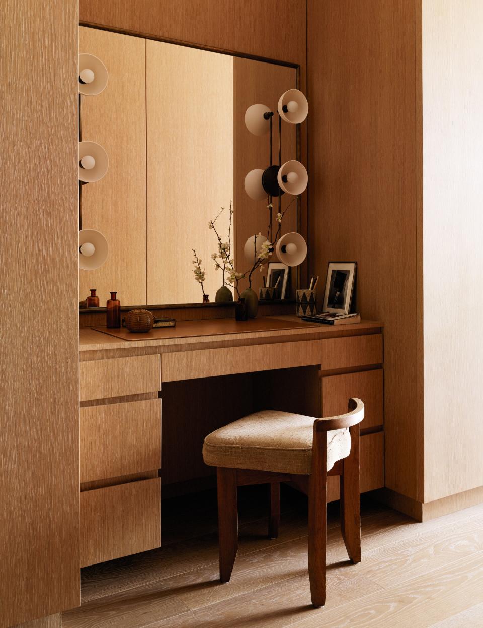 Santos designed the perfect minimalist vanity from custom antique brass and cerused oak with sconces by Apparatus and a small chair by Guillerme et Chambron, purchased from Morentz.