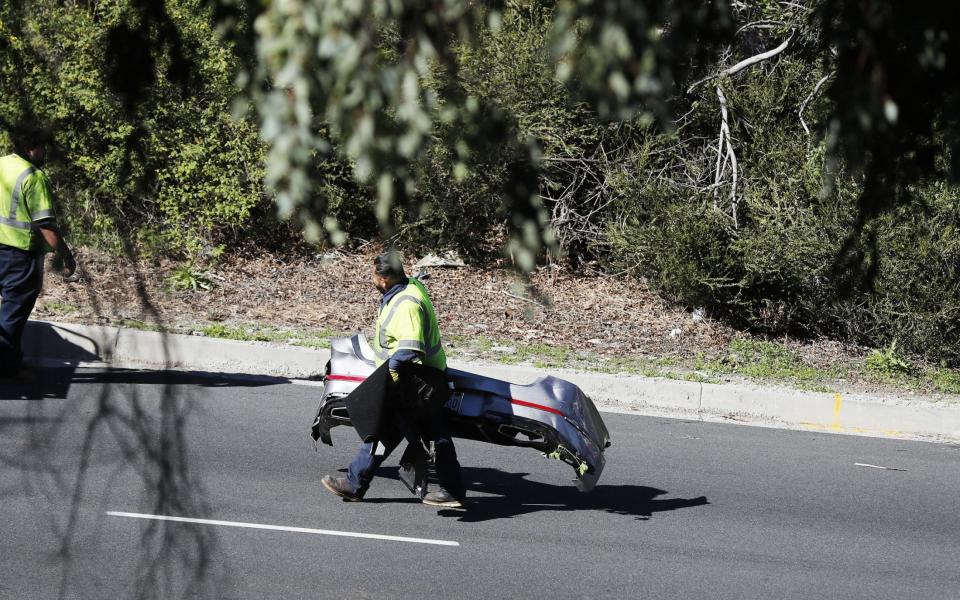 Debris from the vehicle is carried from the scene as a crane is used to pick up a Genesis GV80 SUV driven by US golfer Tiger Woods at the scene of a single-vehicle crash in Rancho Palos Verdes, California - EPA