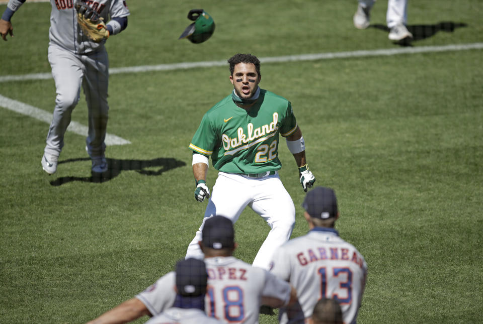 Ramón Laureano on the field in an Oakland jersey. Astros players backs are in the forefront of the photo.