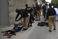 EDITORS NOTE: Graphic content / Police collect evidence next to a body of an alleged gunman outside the Pakistan Stock Exchange building in Karachi on June 29, 2020. - A group of gunmen attacked the Pakistan Stock Exchange in Karachi June 29, police said, with four of the attackers killed. (Photo by Asif HASSAN / AFP) (Photo by ASIF HASSAN/AFP via Getty Images)