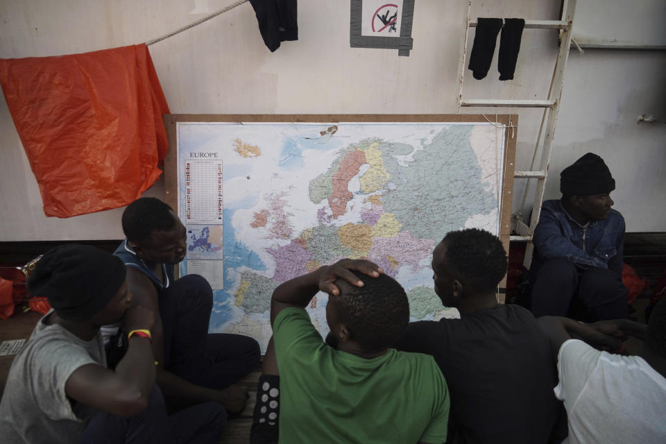 In this Sept. 23, 2019 photo, rescued migrants look at a map of Europe aboard the Ocean Viking humanitarian ship as it sails in the Mediterranean Sea. The misery of migrants in Libya has spawned a thriving and highly lucrative business, in part funded by the EU and enabled by the United Nations, an Associated Press investigation has found. (AP Photo/Renata Brito)