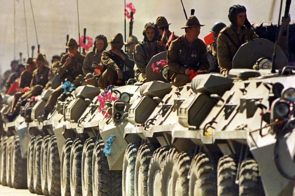 FILE - In this 1988 file photo, Soviet soldiers ride on top of their armored vehicles as they travel along a highway in Kabul heading for the Soviet Union. Afghanistan is marking the 31st anniversary of the Soviet Union's last soldier leaving the country, Saturday, Feb. 15, 2020. This year's anniversary comes as the United States negotiates its own exit after 18 years of war, America's longest. (AP Photo/ Liu Heung-Shing)