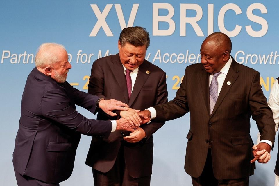 中國領導人習近平（中）在金磚五國高峰會上表現失常，連在台上都必須要巴西總統魯拉（左）抓著他的手放在南非總統拉馬佛沙的手上，才完成合照。   圖：達志影像／路透社
