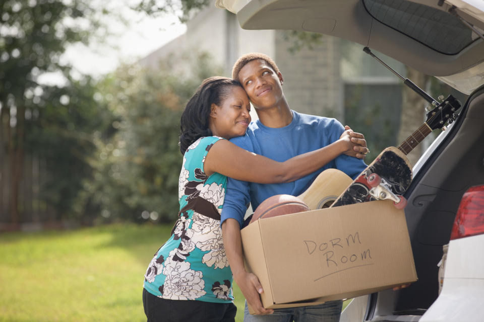 Mother hugging teenage son as he packs for college