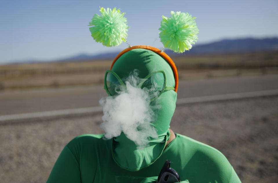 Audrie Clark smokes a vape outside of the Storm Area 51 Basecamp event Friday, Sept. 20, 2019, in Hiko, Nev. The event was inspired by the "Storm Area 51" internet hoax. Thousands of curious Earthlings from around the globe traveled to festivals, and several hundred made forays toward the secret Area 51 military base in the Nevada desert on Friday, drawn by an internet buzz and a social media craze sparked by a summertime Facebook post inviting people to “Storm Area 51.” (AP Photo/John Locher)