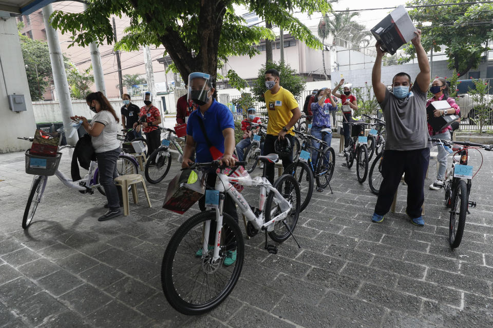 Recipients of the Benjamin Canlas Courage to be Kind Foundation react after getting their bicycles outside a building at the financial district of Manila, Philippines, Saturday, July 11, 2020. Restricted public transportation during the lockdown left many Filipinos walking for hours just to reach their jobs. The foundation saw the need and gave away mountain bikes to nominated individuals who are struggling to hold on to their jobs in a country hard hit by the coronavirus. (AP Photo/Aaron Favila)