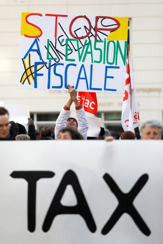 FILE PHOTO: A man holds a placard reading "Stop tax avoidance" during a protest outside the courthouse ahead of the LuxLeaks trial before an appeal court in Luxembourg