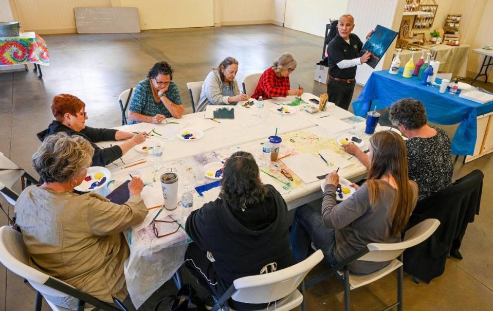 Kirk Cruz, top, leads a senior painting club at River Park shopping center’s Art Groove Gallery on Wednesday, April 5, 2023.