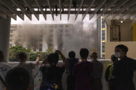 Passerby watch a fire from a footbridge in Cheung Sha Wan, a residential and industrial area, in Hong Kong, Friday, March 24, 2023. (AP Photo/Louise Delmotte)