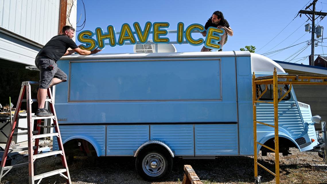 Josh Works, left, lifts a neon sign onto his Frost Bite Shave Ice food truck. Dylan Steinmetz, right, of Element Ten in Kansas City, will install. Works has developed several projects in Humboldt, Kansas, including the Life is Fine Plaza, a gathering spot on the town square that’ll soon be Frost Bite’s permanent home.
