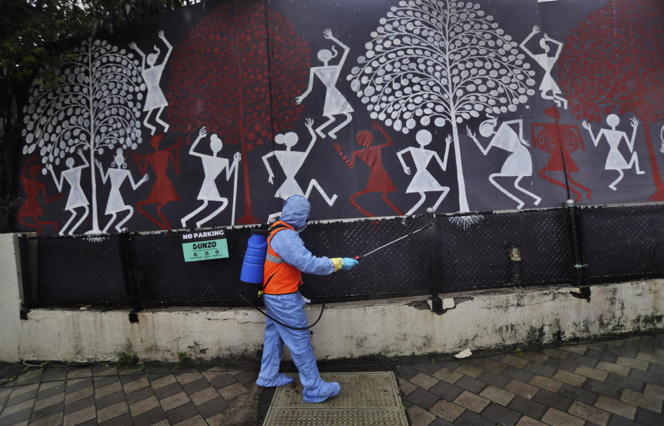 A civic worker sanitizes the gate of Bollywood superstar Amitabh Bachchan's residence after Bachchan and his son Abhishek Bachchan tested positive for the coronavirus and were hospitalized in Mumbai, India, Sunday, July 12, 2020. (AP Photo/Rafiq Maqbool)