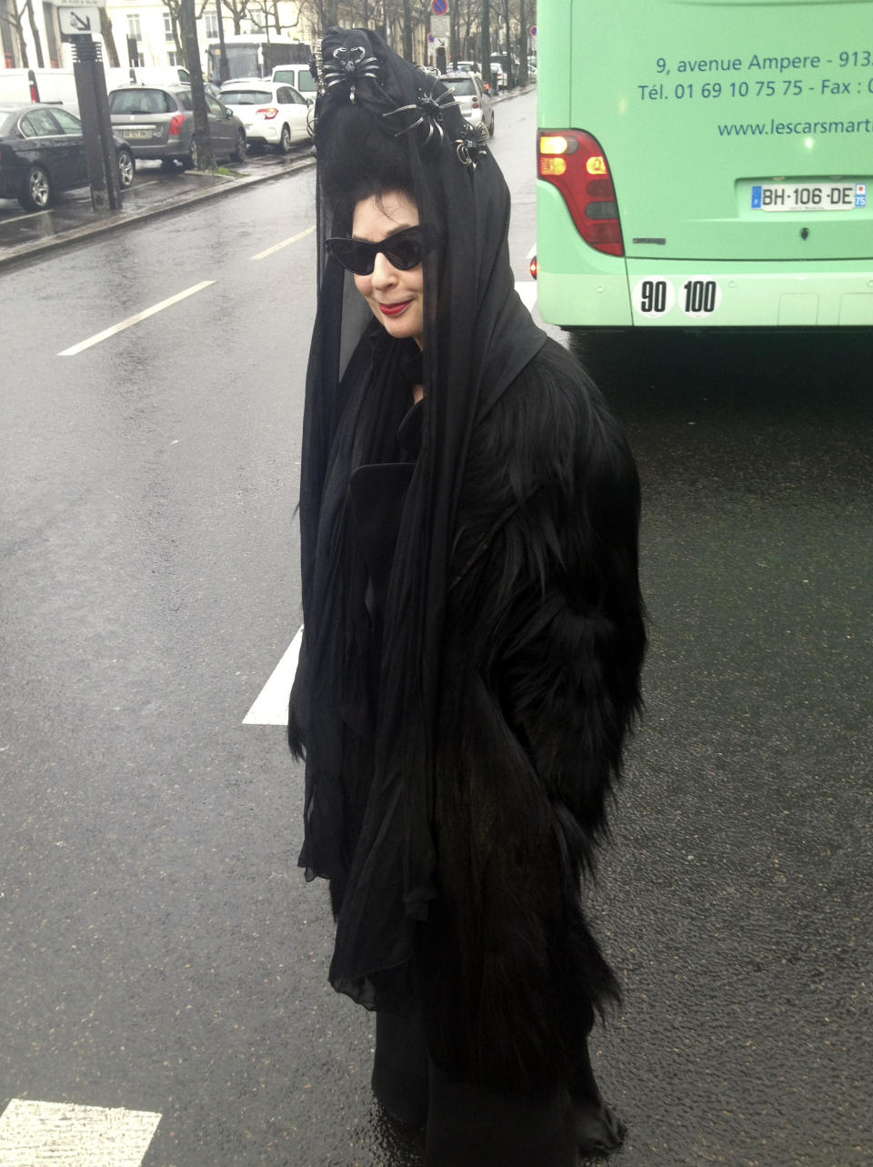 In this photo taken on Thursday, Jan. 16, 2014, Paris-based American-born French fashion blogger Diane Pernet wears a vintage gorilla fur coat before a men's fall-winter 2014-2015 fashion collection in Paris, Thursday, Jan. 16, 2014. The vintage coat made from real gorilla pelt has been condemned by animal rights campaign group PETA. (AP Photo/Thomas Adamson)