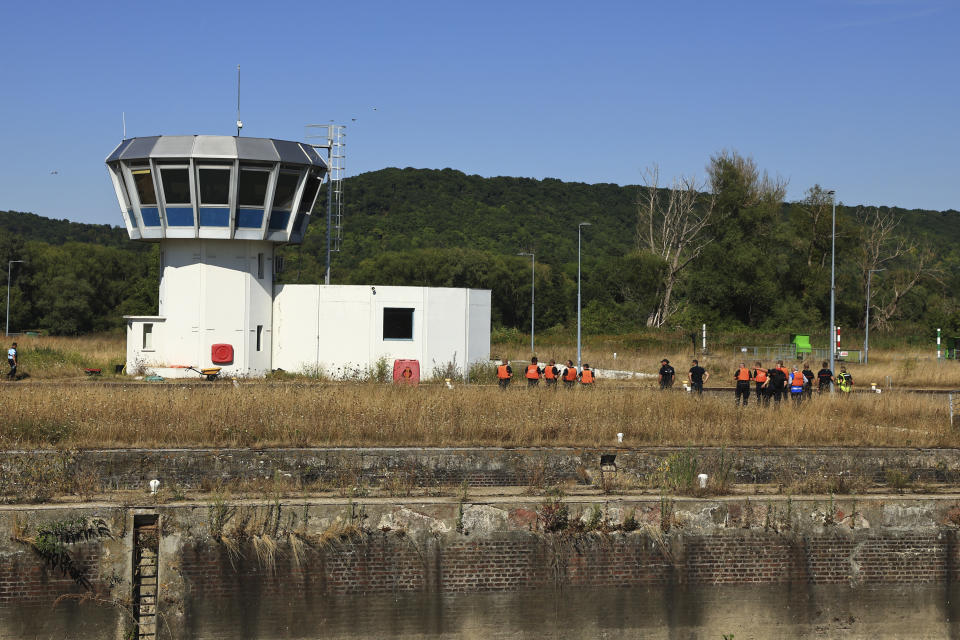 French fire brigade and Sea Sheperds members gather near the lock of Notre Dame de la Garenne where a Beluga whale is being prepared to be moved, in Saint-Pierre-la-Garenne, west of Paris, France, Tuesday, Aug. 9, 2022. French environmentalists are moving a dangerously think Beluga that had strayed into the Seine River last week to a salt-water river basin to try and save its life. Lamya Essemlali, president of Sea Shepherd France, said the ethereal white mammal measuring 4-meters will be transported to the salty water for "a period of care" by medics who suspect the mammal is sick. (AP Photo/Aurelien Morissard)