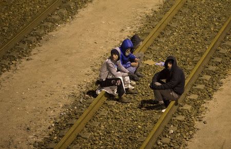 Migrants sit on the railway tracks of the freight shuttle leading to the entrance of the Channel Tunnel in Calais, France, October 14, 2015. REUTERS/Philippe Wojazer