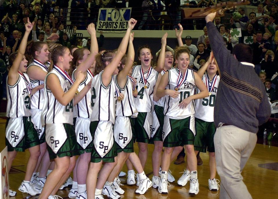 The Portland St Patrick girls basketball team cheers their coach, Al Schrauben, after receiving their medals and trophy following a 57-44 win over Gaylord St. Mary in the 2002 Class D state title game.