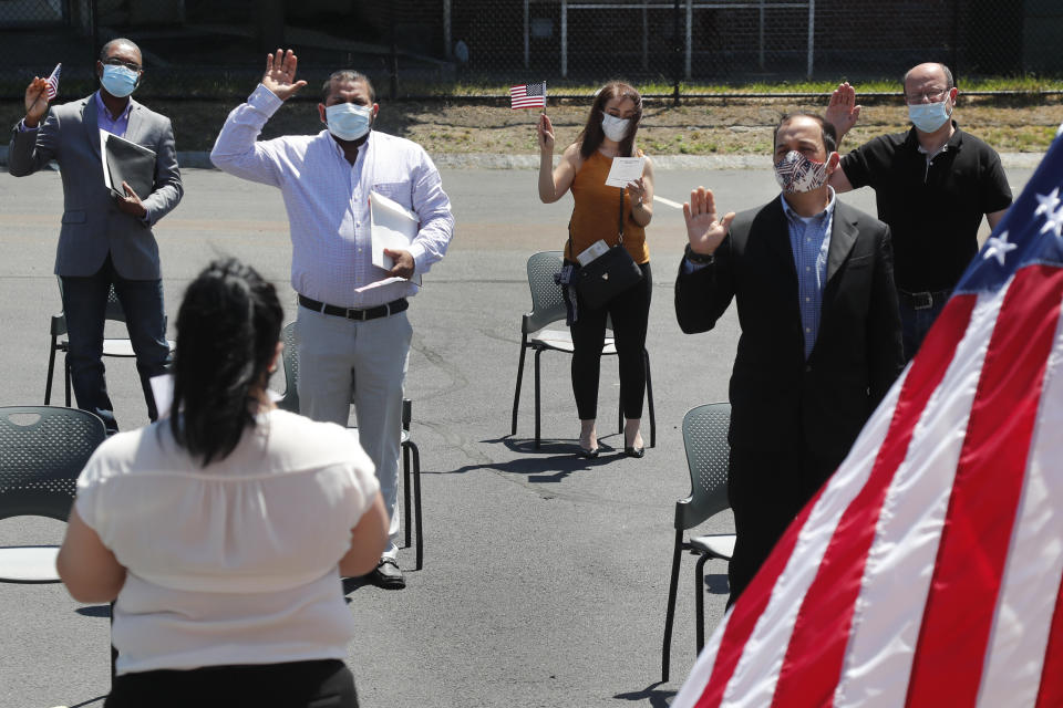 New citizens, socially distanced, are sworn in outside the U.S. Citizenship and Immigration Services building, Thursday, June 4, 2020, in Lawrence, Mass. The federal agency is resuming services in many cities across the country after being shuttered for more than two months because of the coronavirus pandemic. (AP Photo/Elise Amendola)