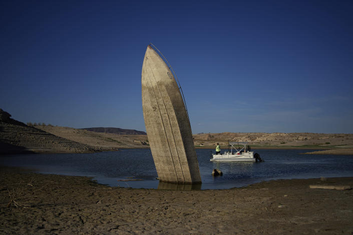 FILE - A formerly sunken boat sits upright into the air with its stern stuck in the mud along the shoreline of Lake Mead at the Lake Mead National Recreation Area, Friday, June 10, 2022, near Boulder City, Nev. Lake Mead water has dropped to levels it hasn't been since the lake initially filled over 80 years earlier. Prolonged drought, climate change and overuse are jeopardizing the water supply that more than 40 million people rely on. States are acknowledging that painful cuts are needed, but also stubbornly clinging to the water they were allocated a century ago. (AP Photo/John Locher, File)