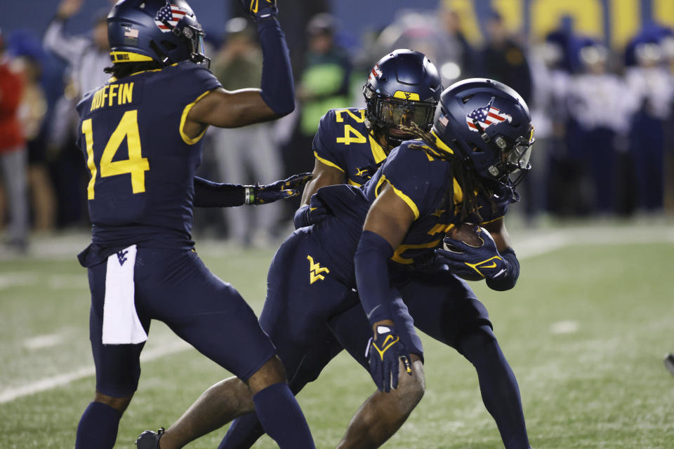 West Virginia's Malachi Ruffin (14) and Marcis Floyd (24) celebrate a fumble recovery by Aubrey Banks, right, during the first half of an NCAA college football game against BYU on Saturday, Nov. 4, 2023, in Morgantown, W.Va. (AP Photo/Chris Jackson)