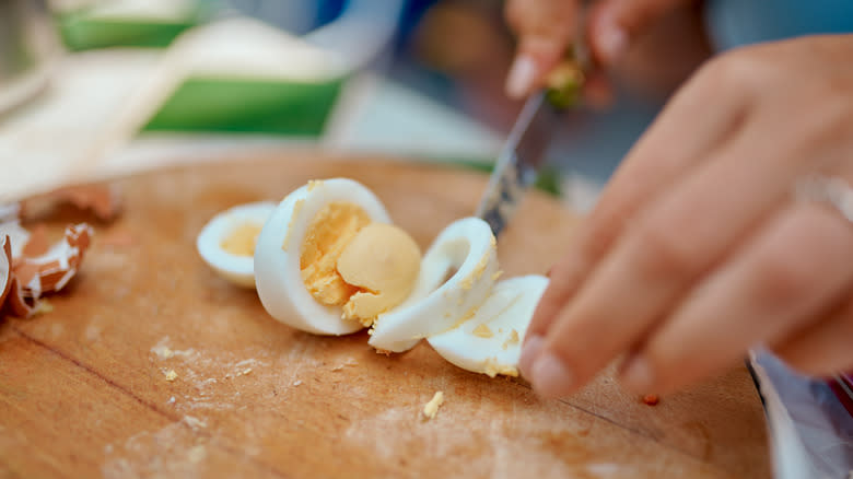 hands slicing boiled egg