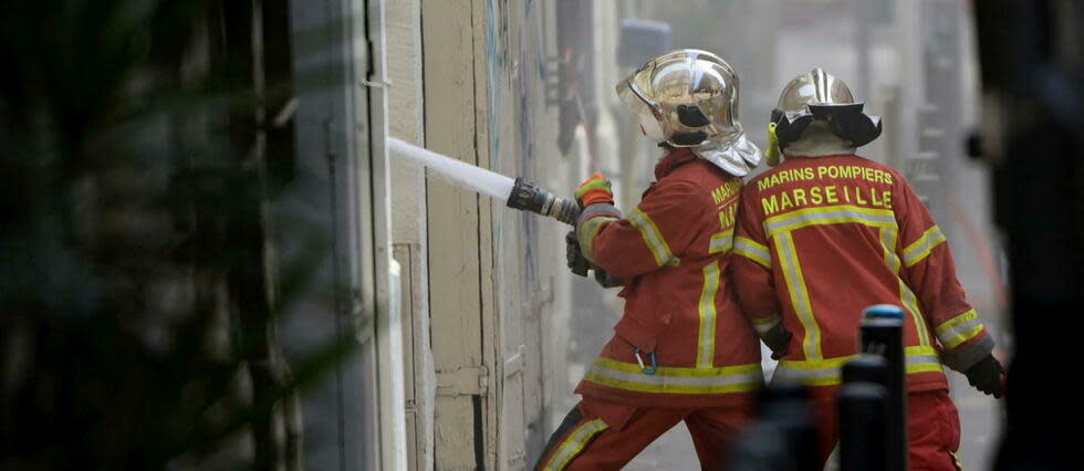 Les pompiers luttaient encore contre le feu dimanche midi rue de Tivoli à Marseille.  - Credit:CLEMENT MAHOUDEAU / AFP