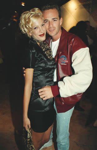 <p>Shutterstock</p> Tori Spelling and Luke Perry at the opening of Plant Hollywood in 1995