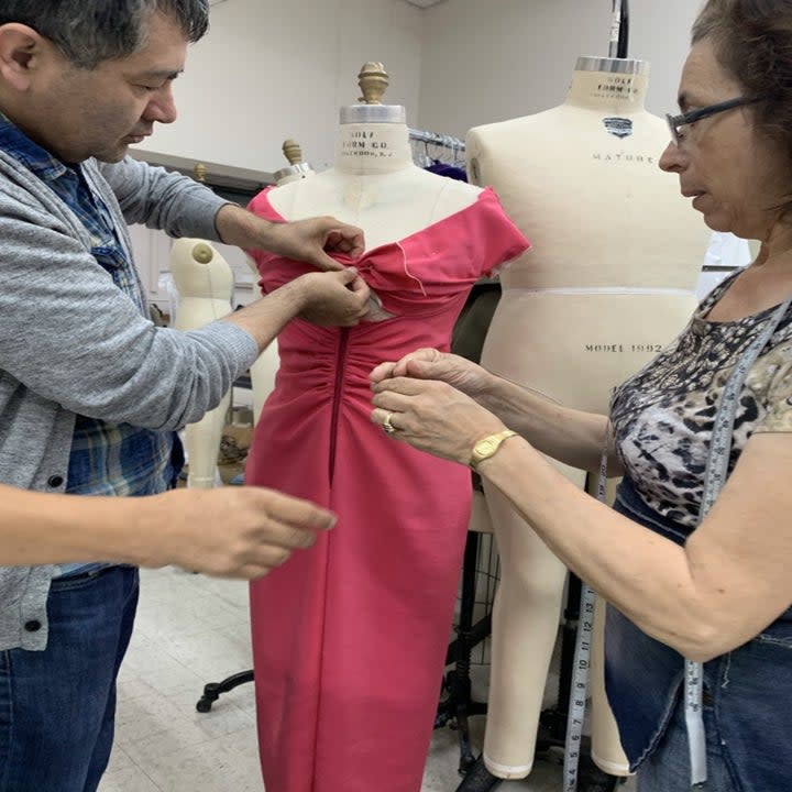 Two people working on a costume on a mannequin