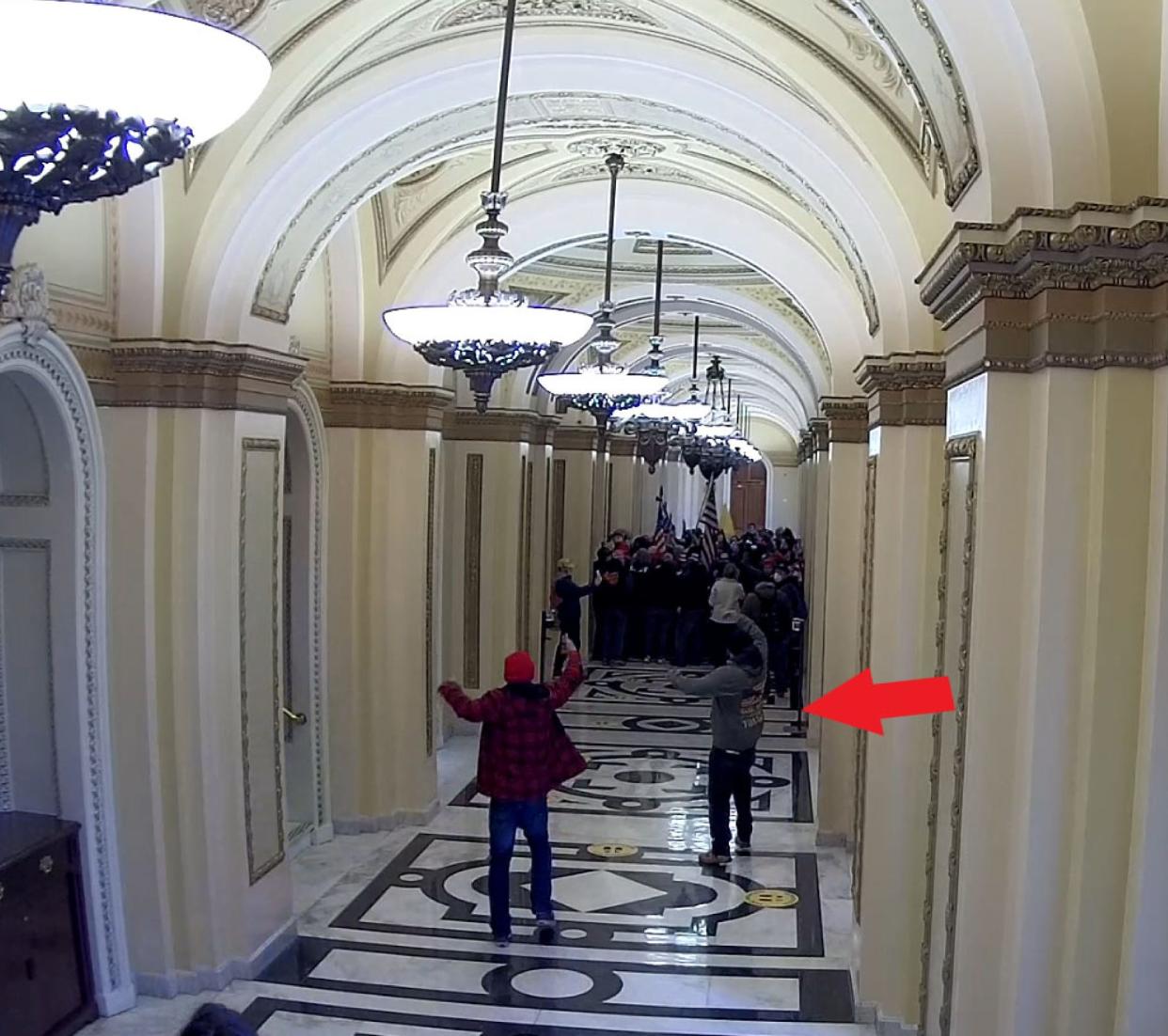 This image of two men waving to a crowd in the Jan. 6, 2021, U.S. Capitol riot was included in a sentencing memo a prosecutor filed about First Coast resident Jeffrey Register. The memo identifies Register as the man marked by an arrow, standing in a hallway leading to the speaker of the House lobby.