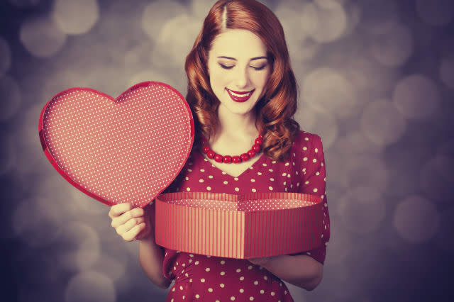 Redhead girl with gift for Valentines Day. Photo with bokeh at background