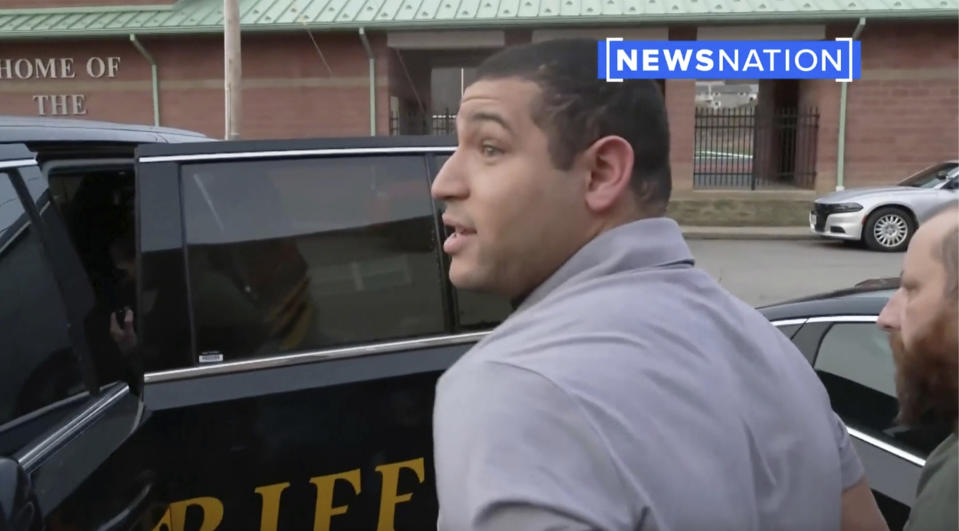 This image taken from video provided by Newsnation/TMX shows reporter Evan Lambert being taken into police custody on Wednesday, Feb. 8, 2023 in East Palestine, Ohio. NewsNation posted video of their correspondent being arrested Wednesday in the gymnasium of an elementary school in East Palestine where Gov. Mike DeWine was giving an update about the accident. Lambert was held for about five hours before being released from jail, NewsNation reported.(Newsnation TMX via AP)