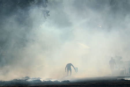 Ranch hands do what they can to try and put out flames after the Lilac Fire, a fast moving wild fire, came through Bonsall, California, U.S., December 7, 2017. REUTERS/Mike Blake