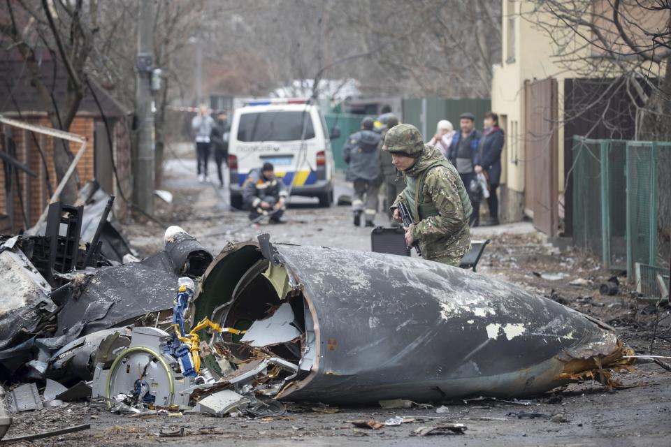 A Ukrainian Army soldier inspects fragments of a downed aircraft in Kyiv, Ukraine, Friday, Feb. 25, 2022. It was unclear what aircraft crashed and what brought it down amid the Russian invasion in Ukraine. Russia is pressing its invasion of Ukraine to the outskirts of the capital after unleashing airstrikes on cities and military bases and sending in troops and tanks from three sides. (AP Photo/Vadim Zamirovsky)